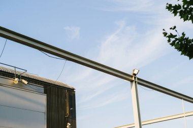 Önde lambalar ve hoparlörlü metal kutuplar - arkaplanda bulutlu gökyüzü