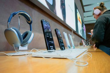 Paris, Fransa - 22 Eylül 2022: Yeni Apple AirPods Max dinleyen genç kız müşteri 14 Pro Max iPhone menzilinin yanında