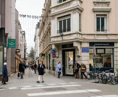 Strasbourg, France - Jan 5 2023: View of large Pt Rue de lEglise with Art Gallery iamd pedestrians walking with Christmas tree in background