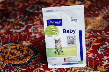 Paris, France - Dec 16, 2022: Open package with Virbac Baby Pre Neutered Cat dry pet food on the silk rug in living room - elevated view