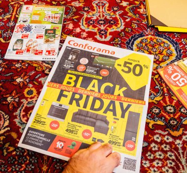 Paris, France - Dec 2, 2022: Advertising leaflets of Conforama supermarket chain selling furniture, electronics home object - man reading on the living room silk rug