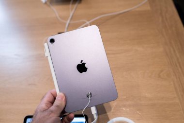 Paris, France - Oct 28, 2022: POV male hand looking holding latest iPad 10th mini generation looking at rear camera pink colored device