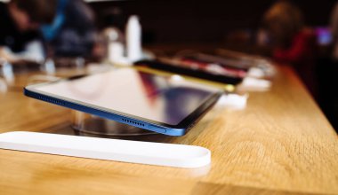 Paris, France - Oct 28, 2022: Hero object side view of new Apple Computers iPad 10th generation in Blue color in store - customers silhouettes shopping in background