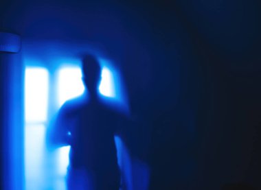 Silhouette shadow of a woman on a blue wall with white lamp in the left corner