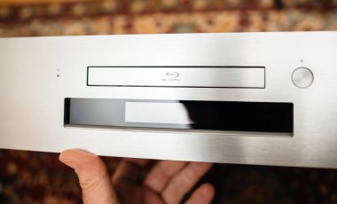 Paris, France - Oct 18, 2023: POV male hand holding new Onkyo BD-SP809 top-of-the-range Blu-ray deck with large digital display screen