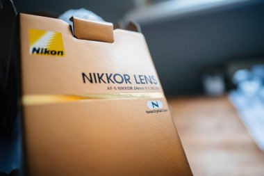 Paris, France - Jan 16, 2023: Close-up focus on the cardboard package of open new NIkon AF-s Nikkor 25mm f 1.8 G ED lens for DSLR camera