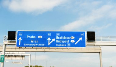 Signage blue traffic on the expressway with inscription Praha, Wien, Simmeringer haide, Bratislava, Budapest and Aiport Flughafen