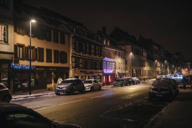Strasbourg, France - Dec 19, 2022: Night scene of the city of Strasbourg with parked cars and holidays illumination near the windows