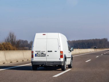 Germany - Circa 2023: Rear view of white Ford Transit connect mini van on the almost empty highway on a winter day - commuting driving in germany