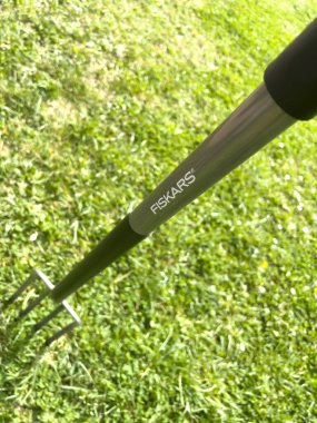 Almanya - 13 Nisan 2022: Yeni bir Fiskars zemin çatalı yeşil bahçe arka planının yukarıdan görüntüsü