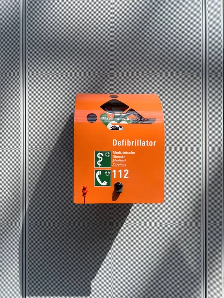 Defibrillator inside a modern Airport with text in multiple languages and 112 rescue phone number