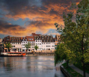 Strasbourgs Rustic River Cityscape Sunset 'te güzel hasta nehir ve teknelerle - ihtişamlı keresteli Alsas evleri arka planda - kırmızı günbatımı