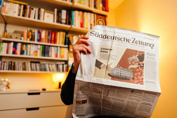 2023年3月20日 女性在客厅里阅读最新一期德国报纸 该报在头版刊登了瑞士银行历史性收购竞争对手瑞士信贷集团 Credit Suisse Group 的重大新闻 Vitsoe 606 — 图库照片