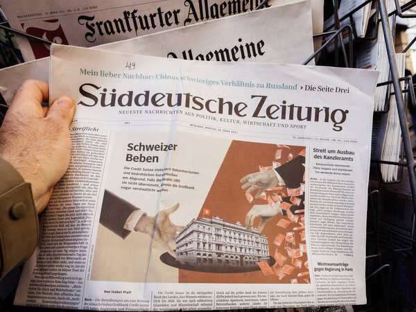 Paris, France - Mar 20, 2023: Suddeutsche Zeitung breaking news of UBS historic acquisition of rival Credit Suisse Group AG - male hand buying press at press kiosk