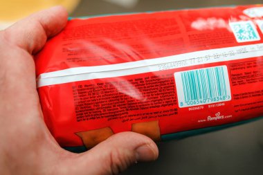 Frankfurt, Almanya - 18 Mar 2023: PoV erkek elinde yeni Pampers bebek kurutma pantolonu paketinde okuma uyarıları var - ideal uyumu kolay, 12 saate kadar dermo testi yapıldı,