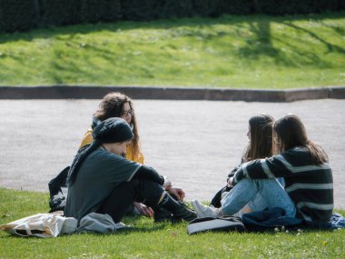 Strasborg, Fransa - 29 Mar 2023: Bir grup genç yetişkin Strasbourg 'daki cumhuriyet parkında güneşli bir günün tadını çıkarıyorlar. Yeşil manzara, sakin yürüyüşler ve dostluk için mükemmel bir zemin sağlar..