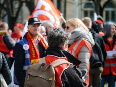 Strasborg, Fransa - 29 Mart 2023: kıdemli kadının arka görüşü - yetişkinler Fransa 'da emeklilik reformunu protesto ediyorlar, sarı yelek giyiyorlar ve tarihi bir devrim için birlikte yürüyorlar..