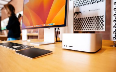 Paris, Fransa - 20 Mart 2023: Güçlü ve küçük Mac stüdyosu, Apple Computers 'dan bir masaüstü bilgisayarı, arka planda çalışan dahi kadın işçinin masadaki silüeti