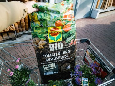 Frankfurt, Almanya - 4 Mar 2023: Süpermarket DIY 'de erkek müşteri el ele tutuşması Compo Bio Bio organik domates ve sebze paketinin bahçıvanlığı.