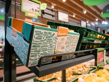 Frankfurt, Almanya - 4 Mart 2023: Demeter marka meyve ve sebzelerle dolu raflar ve kutularla dolu, parlak ve yoğun bir market içi.