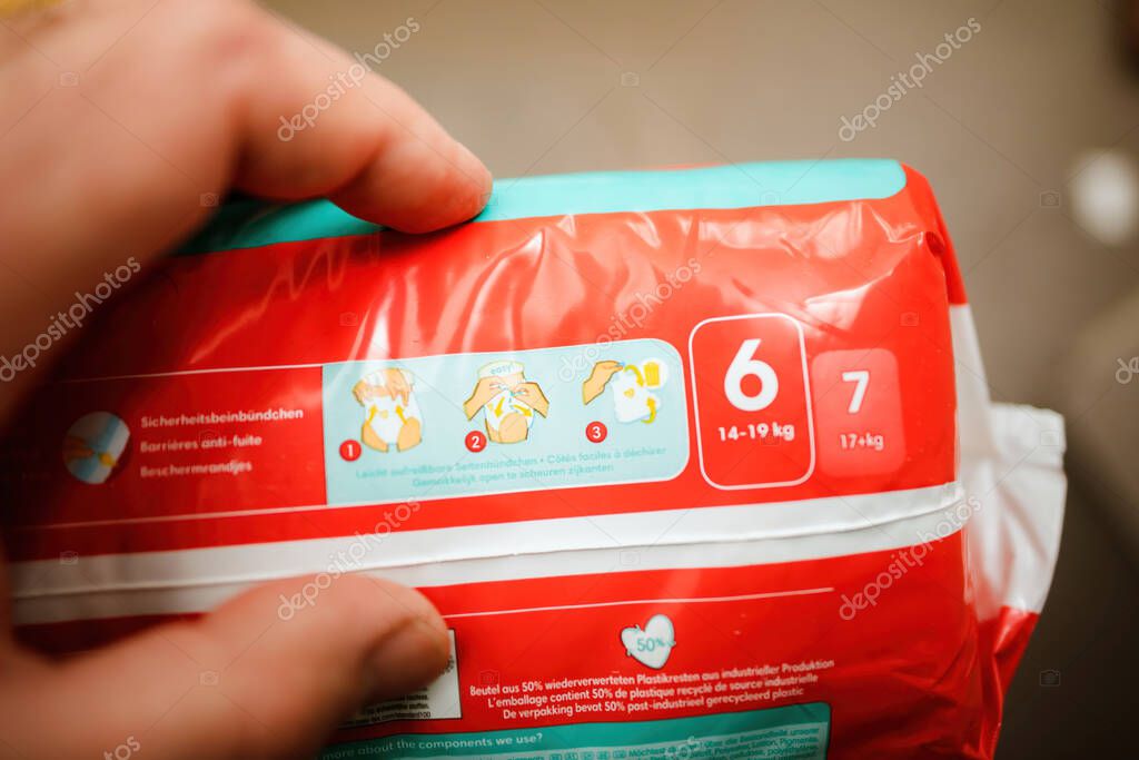 Frankfurt, Germany - Mar 18, 2023: A male hand holds a package of red Pampers Baby-Dry Pants, dermatologically tested for ideal fit and up to 12 hours protection.