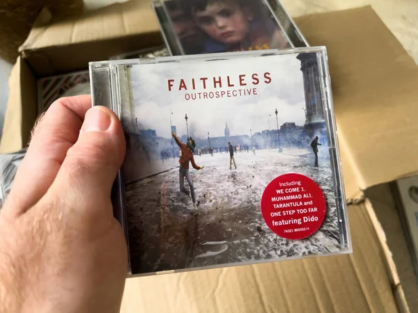 Paris, Fransa - 1 Ocak 13, 2023: Bir adamın elinde karton bir kutu tutması, Faithless 'ın klasik medya kayıtlarından oluşan bir albümü açması