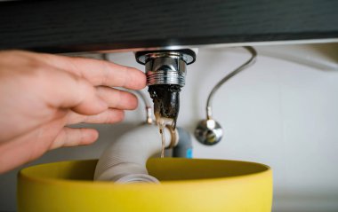 Kişisel bakış açısı- Bir kişi tuvaletteki tıkanmış lavabo giderini temizliyor..