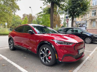 Paris, Fransa - 18 Şubat 2022: Kırmızı elektrikli Mustang SUV Volkswagen arabasının yakınındaki hareketli bir şehir merkezinde duruyor ve ağaçlarla çevrili..
