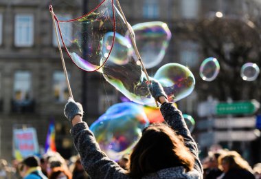 Açık havada eğlenen bir kadın elleriyle komik sabun balonları yapıyor. Taze ve yaratıcı.