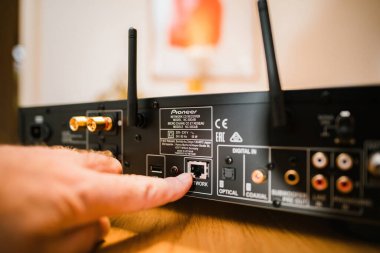 Frankfurt, Almanya - 30 Ocak 2023: Pioneer NC-50DAB Ağ CD Alıcısı 'nı açan bir kişi, RJ-45 ağ kablosu aracılığıyla internet müzik yayınları için teknolojiye bağlıyor.