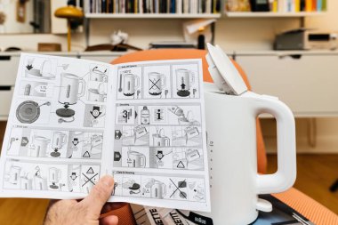 Paris, Fransa - 23 Ocak 2023: POV erkek eli, arka planda Vitsoe 606 raflarıyla oturma odasında Braun Breakfast 1 su ısıtıcısı WK 1100 'ü açıyor