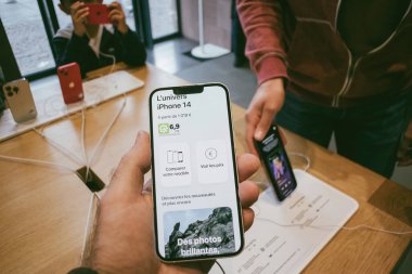 Paris, Fransa - 22 Eylül 2022: Bir kişi, en son kablosuz teknoloji ile çevrili modern bir mağazada yeni bir iPhone 14 Apple bilgisayarına sahip - arka plandaki 1019 avroluk cihazı - müşterileri karşılaştır