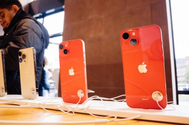 Paris, France - Sep 22, 2022: A row of new iPhone Pro 14 Max phones in Apple Store, with customers in the background. An iconic tech hero object indoors. clipart