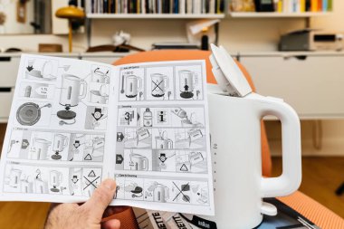 Paris, Fransa - 23 Ocak 2023: POV erkek eli, arka planda Vitsoe 606 raflarıyla oturma odasında Braun Breakfast 1 su ısıtıcısı WK 1100 'ü açıyor