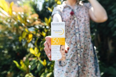 PAris, Fransa - 3 Haziran 2023: Yeni Potoderm Spot-Age SPF50 Plus güneş bakımı paketi taşıyan kişi, kırışıklıkları ve yaş noktalarını azaltıyor, antioksidan takviyesiyle, sarı sahnede iletişim kuruyor - yeşil bahçe