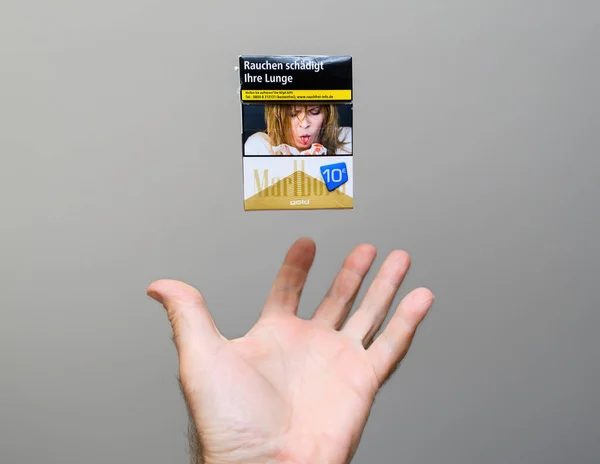 2023年5月30日 接住一个万宝路香烟包装的手在灰色背景下漂浮在空中 有害健康的生命概念 — 图库照片