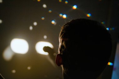 Bir çocuk, içinde üç boyutlu bir dünyayı yansıtan bir kristal küreyi tutuyor. Işık ve gölge prizmada şekiller ve dokular yaratır..