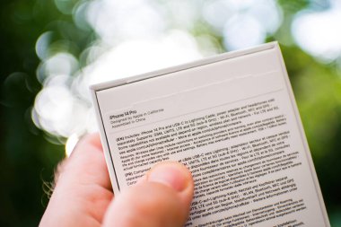 Londra, Birleşik Krallık - 28 Eylül 2022: En son iPhone 14 Pro akıllı telefon paketi ve arka planda bulanıklaştırılmış bahçe