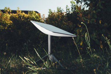 Germany - Jun 16, 2023: One Starlink antenna stands in a garden at sunset, searching for SpaceX satellites. Illustrative editorial for business and reliable internet connection where no mobile clipart