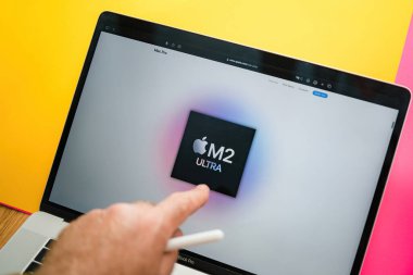 Paris, Fransa - 6 Haziran 2023: 24 çekirdekli 60 çekirdekli GPU ve 32 çekirdekli nöral motor ile yeni M2 Ultra 'yı işaret etmek - Apple' ın dizüstü bilgisayar sergilenen web sayfası ile yaratıcı oda tablosu - kullanıcı el etkileşimi
