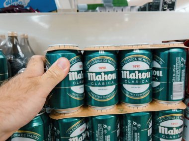 Mallorca, İspanya - 28 Haziran 2023: Bir el, süpermarkette bir kutu Mahou Clasica birası almaya hazır..