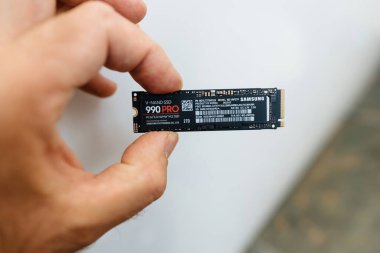 Frankfurt, Almanya - 15 Haziran 2023: Samsung 990 Pro V-nand sssd NVMe SSD bilgisayar sürücüsünün açılışı sırasında el pençe divan duran erkek.