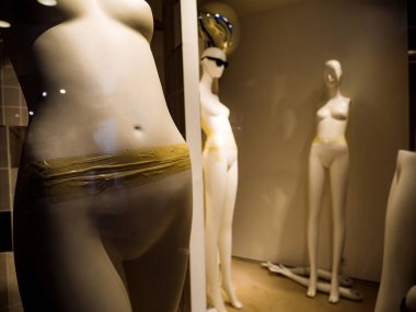 Moda ürünleri ve kadın siluetleri sergilenen terk edilmiş perakende vitrinleri.