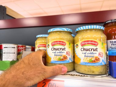 Mallorca, İspanya - 22 Haziran 2023: Pov erkek elinde cam kavanoz ile lezzetli Alman lahana turşusu, Chucrut üretimi Hengstenberg
