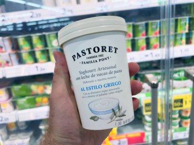 Mallorca, İspanya - 22 Haziran 2023: Erkek el alışverişi Pastorets lezzetli Familia Pont Artisanal Yoğurt. Çayırda yetişen ineklerin sütünden yapılan bu Yunan usulü yoğurt, hiç olmadığı kadar hoşgörü vaat ediyor.