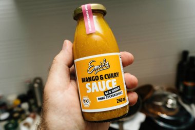 Paris, Fransa - Haziran 3 2023: Mango ve Curry soslu mutfak şişesinde erkek el ele tutuşmak - biyo-organik üretim 250 ml - pişirmeye hazır
