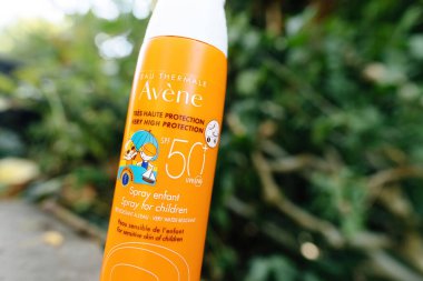 PAris, Fransa - 3 Haziran 2023: Çocuklar için SPF 50 sağlayan Avene Çocukları Koruma Kremi 'nin yakın çekimi. Canlı sarı bir çiçek, bokeh ve yemyeşil bitkilerle süslenmiş resim gibi bir manzara gözler önüne seriliyor..