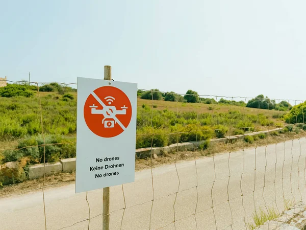 フェンスの赤い注意標識は 制限区域と飛行禁止区域を警告しています 署名のテキストによる通信は 農村部のプライベートエリアの隣のセキュリティと安全性を向上させます 無人機はありません ドローンを維持します — ストック写真