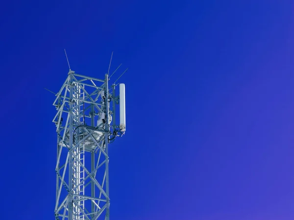 在晴朗的天空中 高耸的蓝塔代表着快速的全球通讯 它的低角度视图展示了用于数据传输和无线技术的电信设备 — 图库照片