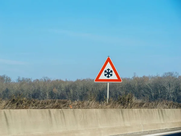 農村部の高速道路上の注意を引く道路標識は 旅行の安全性を確保し 氷の状態を警告します いいえ人々 穏やかな空 赤い三角形の雪の結晶 — ストック写真